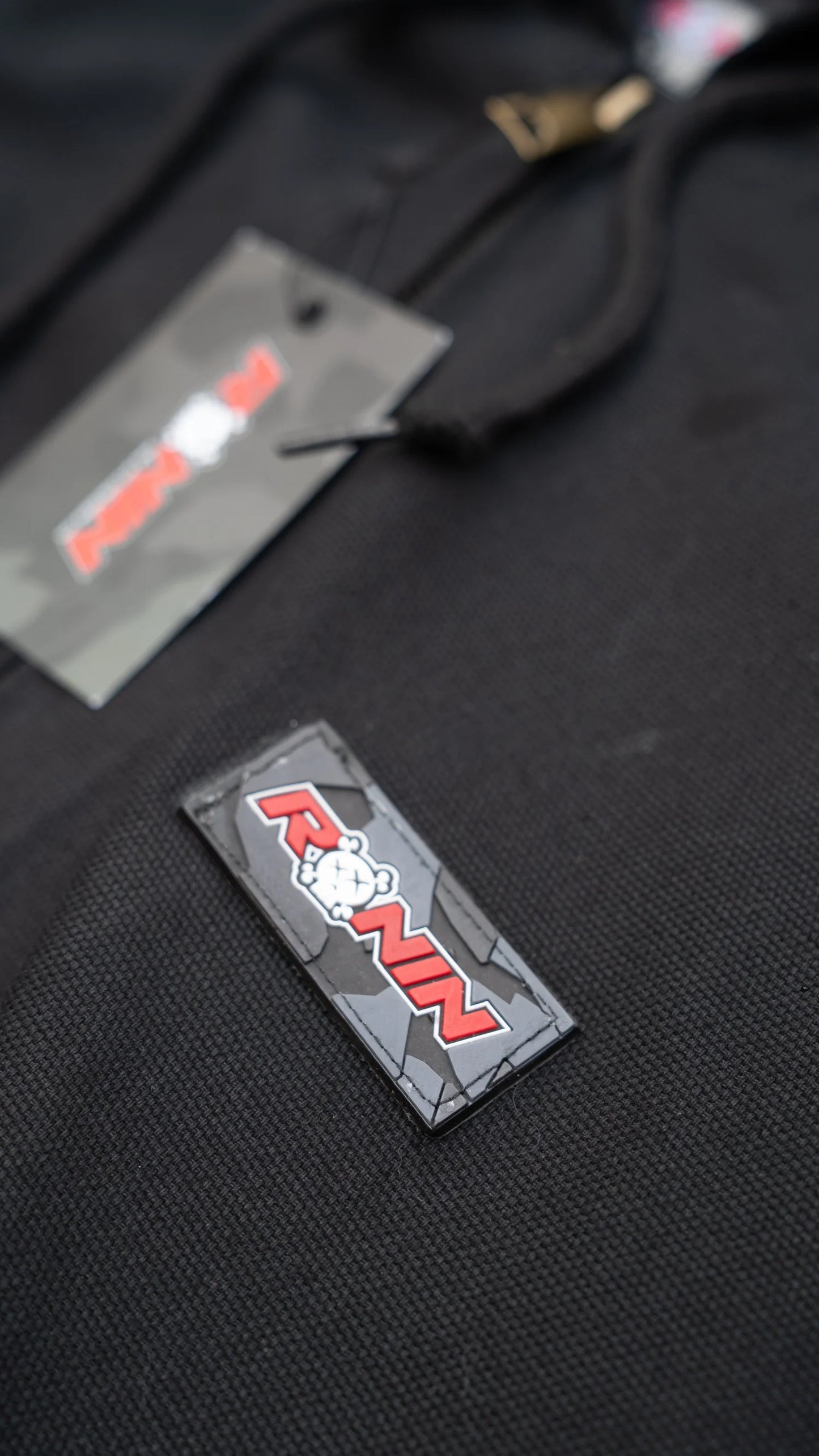 Black jacket with a patch and a tag on a black background