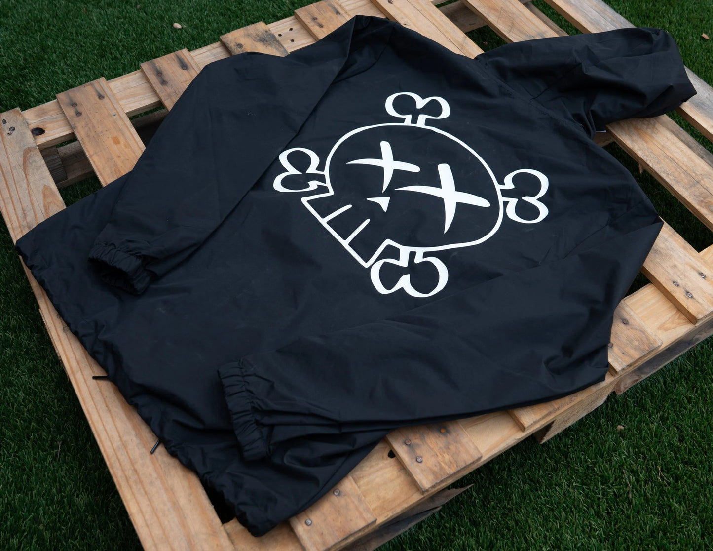Black Hooded Jacket with a white graphic skull logo design on a wooden pallet
