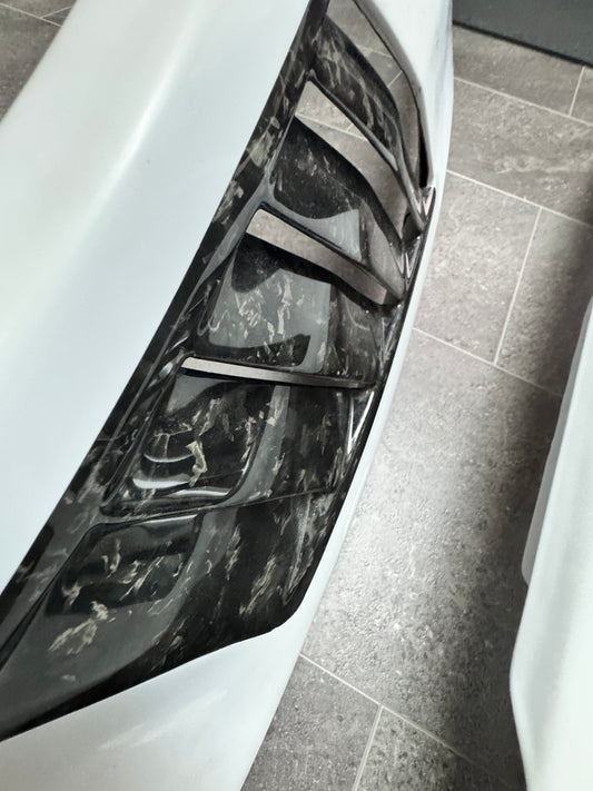 Close-up of a car's front fenders with a forged carbon fiber vents.