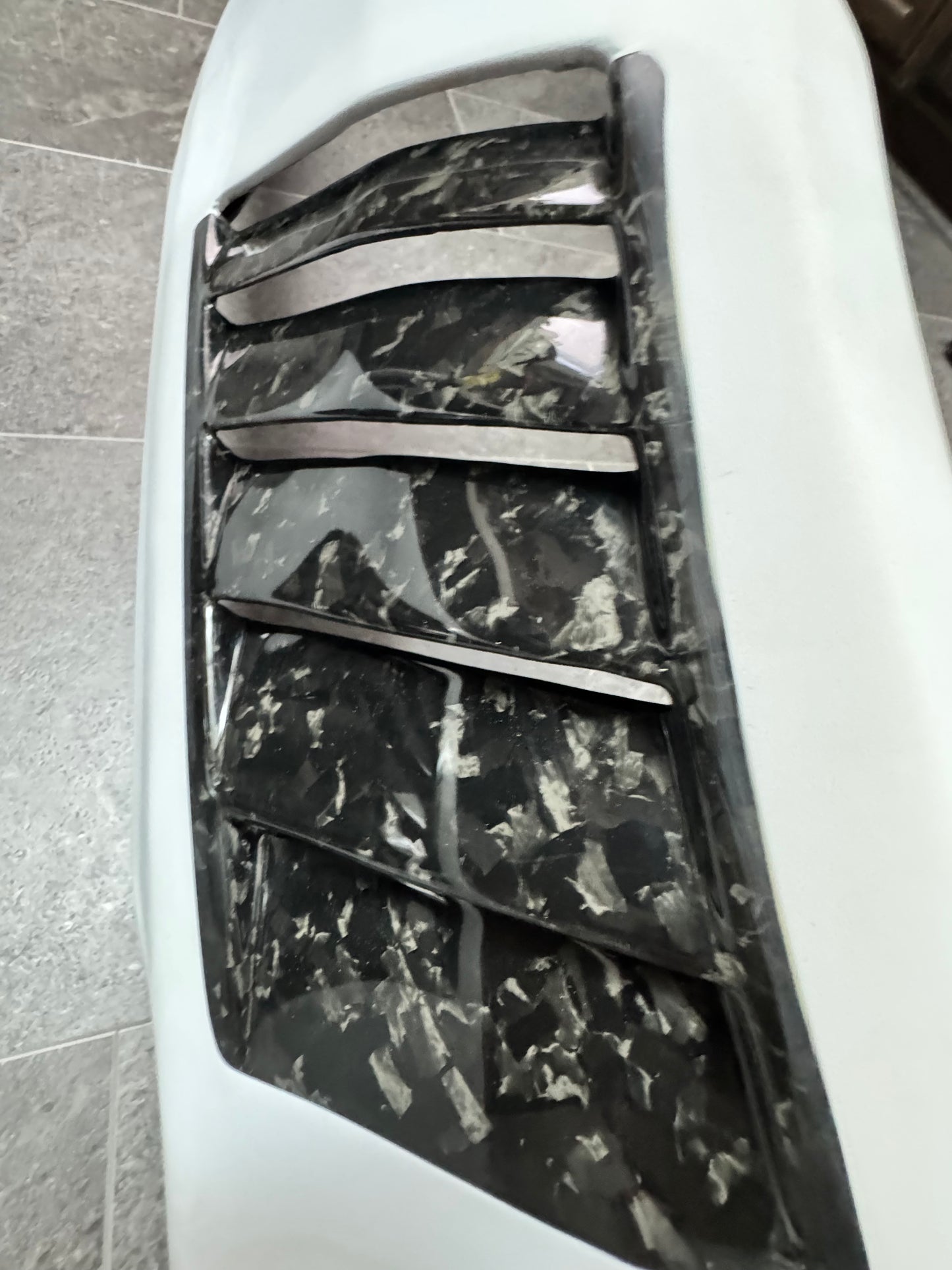 Close-up of a car's front fenders with a forged carbon fiber vents.