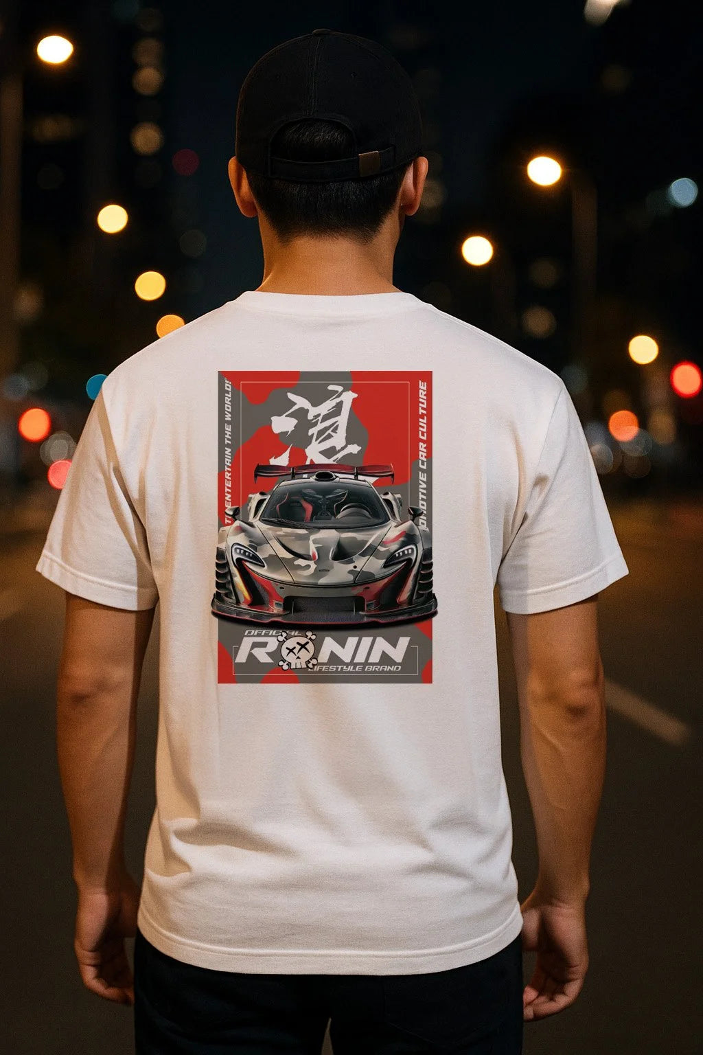 Person wearing a white t-shirt with a graphic design of a McLaren P1 on the back, standing on a street at night.