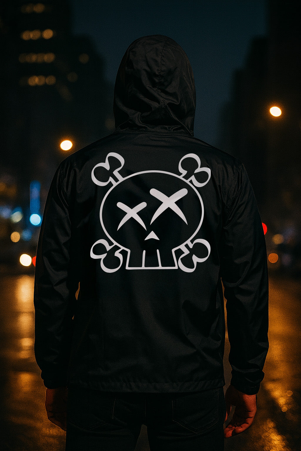 Person wearing a black hoodie with a white skull and crossbones design on the back, standing in a city street at night.