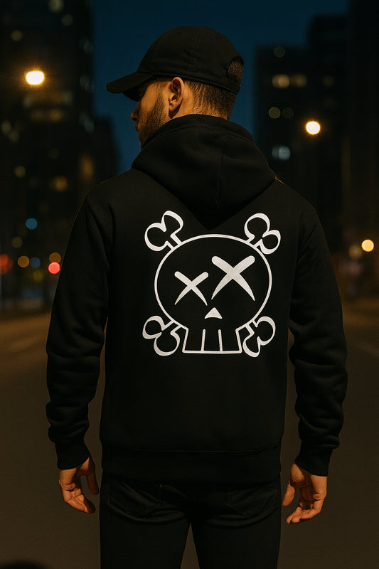 Person wearing a black hoodie with a white skull and crossbones design on the back, standing in an urban setting at night.
