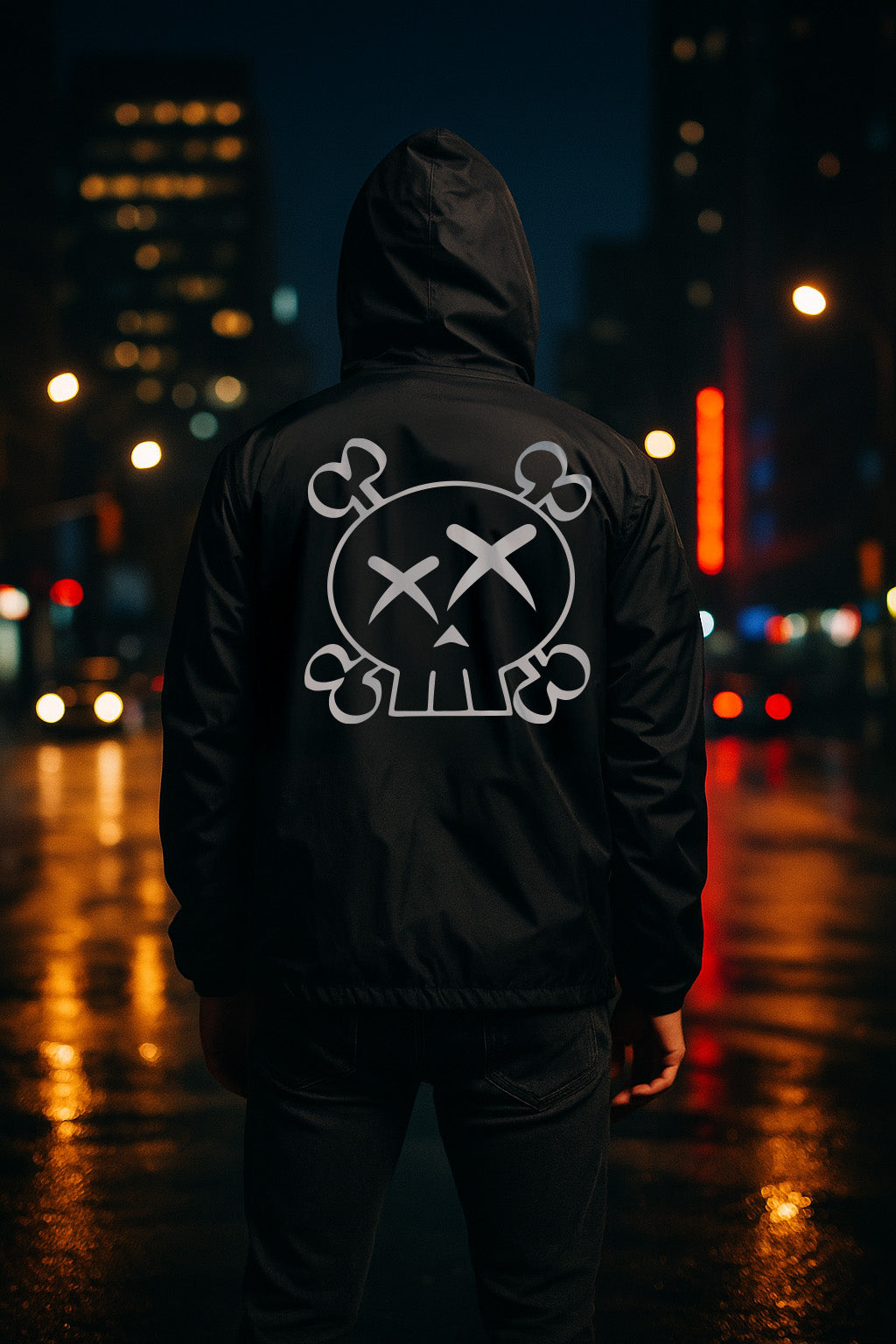 Person wearing a black hoodie with a white skull logo on the back, standing in a city street at night.