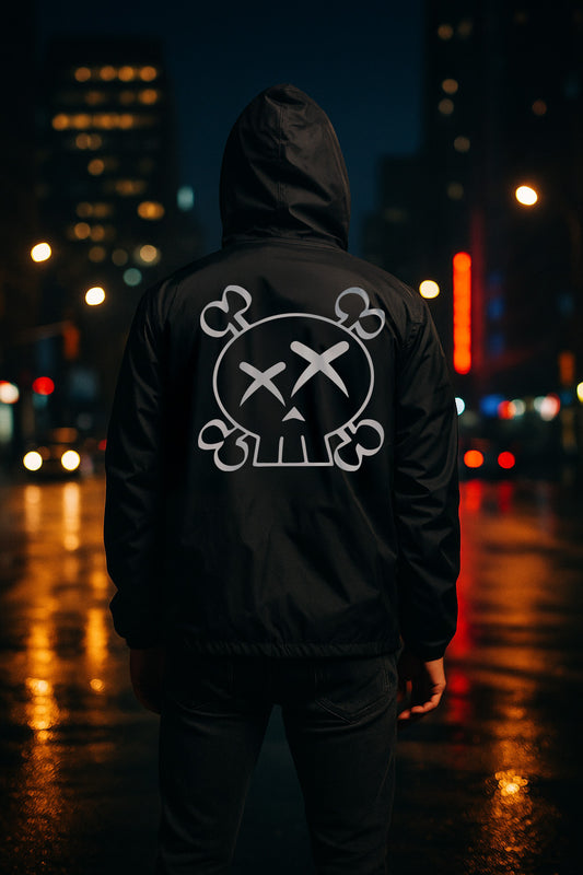 Person wearing a black hoodie with a white skull logo on the back, standing in a city street at night.