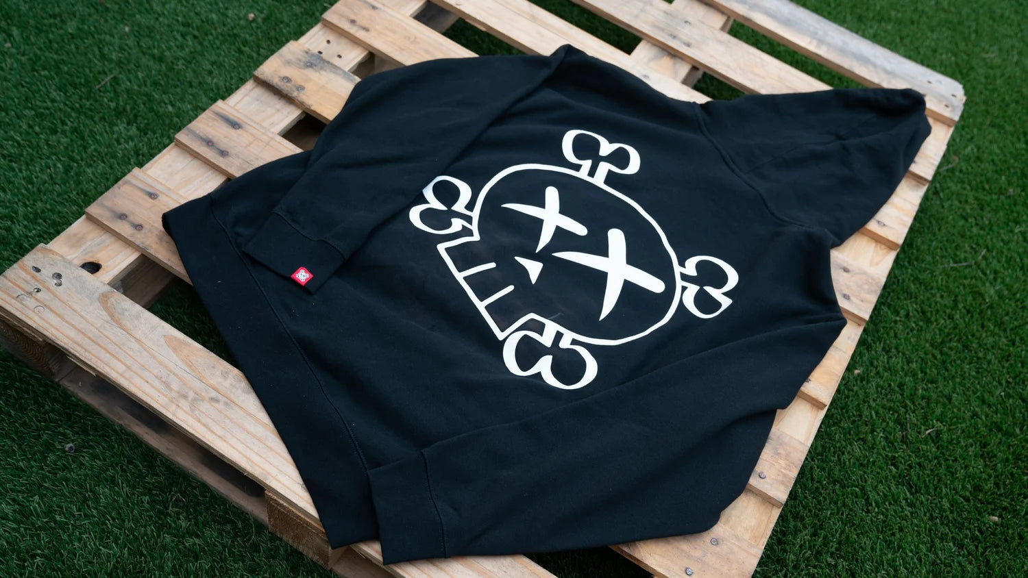 Black t-shirt with a white graphic skull design on a wooden pallet