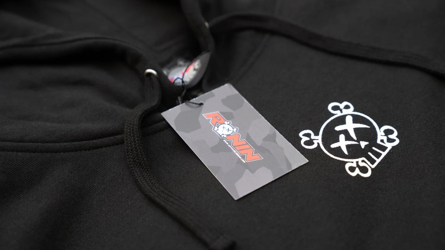 Black hoodie with a brand tag and logo on a dark background