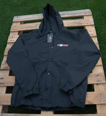 Black jacket with a brand logo on a wooden pallet against a grassy background
