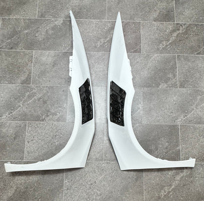 Two white front fenders for a Lamborghini Huracan with forged carbon vents.