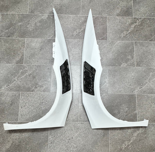 Two white front fenders for a Lamborghini Huracan with forged carbon vents.