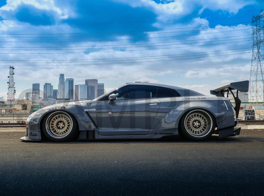 Gray sports car with open door on a road with city skyline in the background