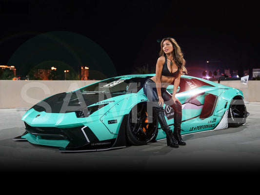 Woman posing next to a turquoise sports car with visible branding at night.